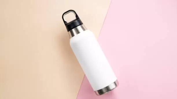 after exercise asian woman drinking water from travel mug